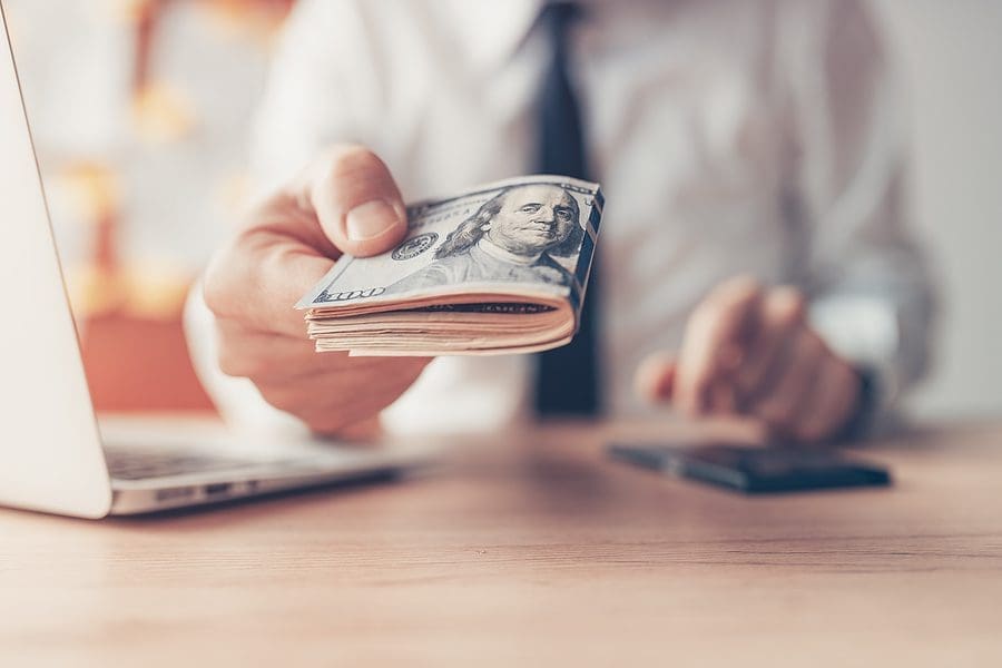 Financial loan, businessman offering US dollar paper currency cash money, close up with selective focus