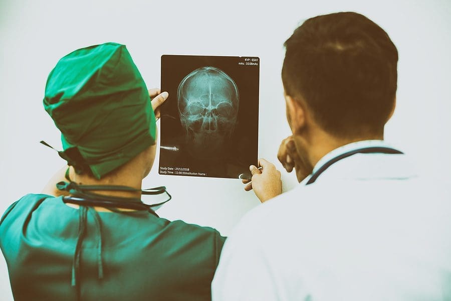 Doctor And Surgeon Examining X-ray Film Of Patient