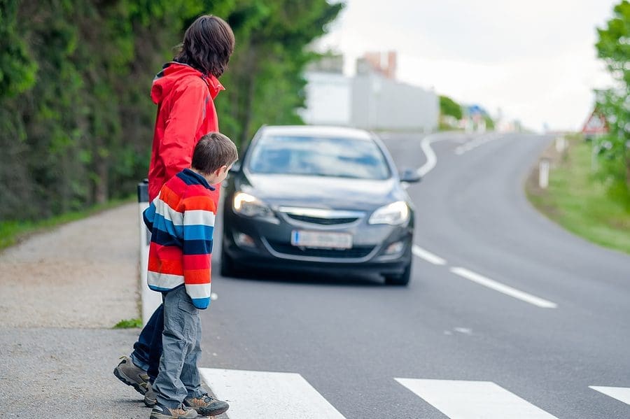 Mom and young son crossing the street while a car approaches