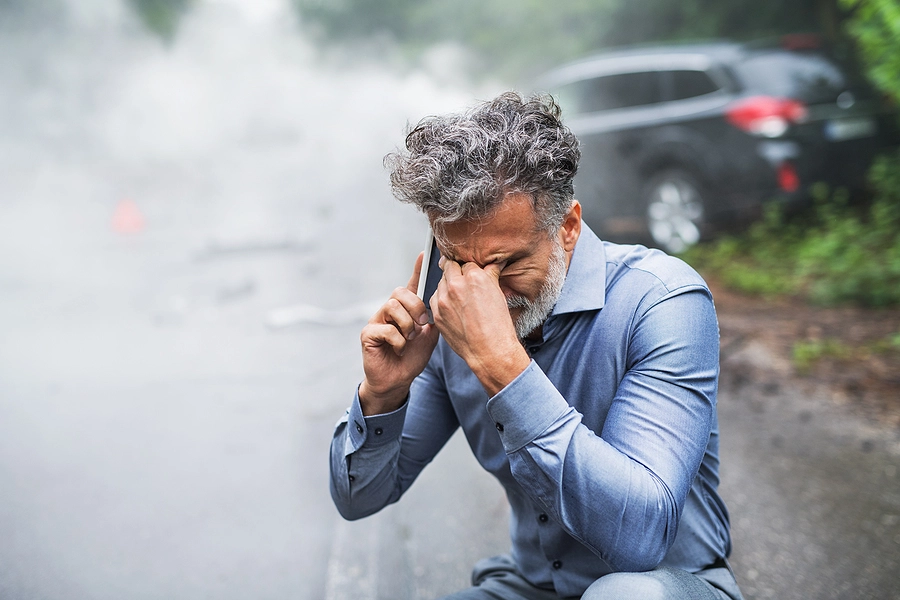 older man suffering from blunt force trauma symptoms after a car accident calling for help